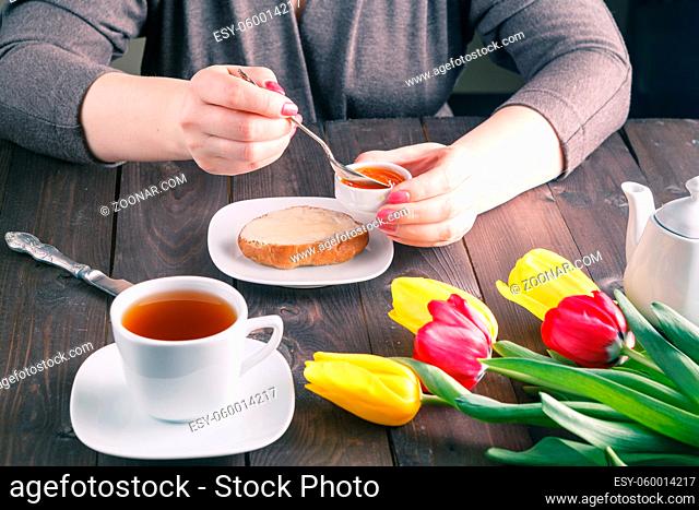Woman hands buttering bread with cup of tea