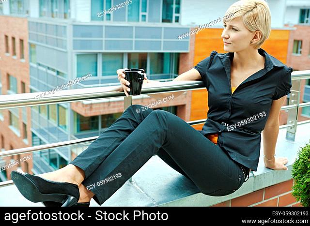 Businesswoman having break on office terrace outdoor drinking coffee