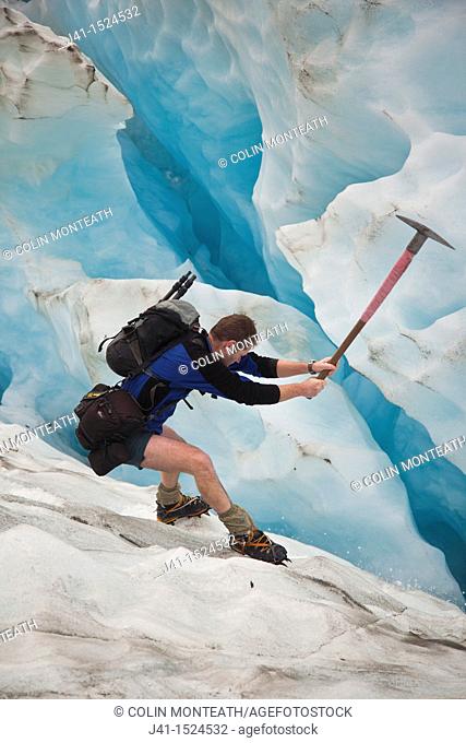 Glacier guide cuts steps in crevasse wall, Franz Josef Glacier, Westland National Park, West Coast of South Island, New Zealand