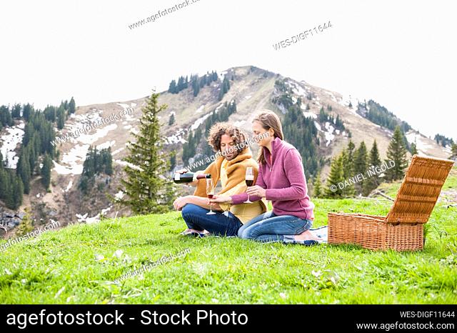Mid adult couple enjoying drink during picnic against mountain