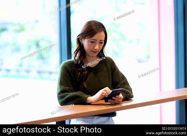 Woman waiting in cafe with smartphone