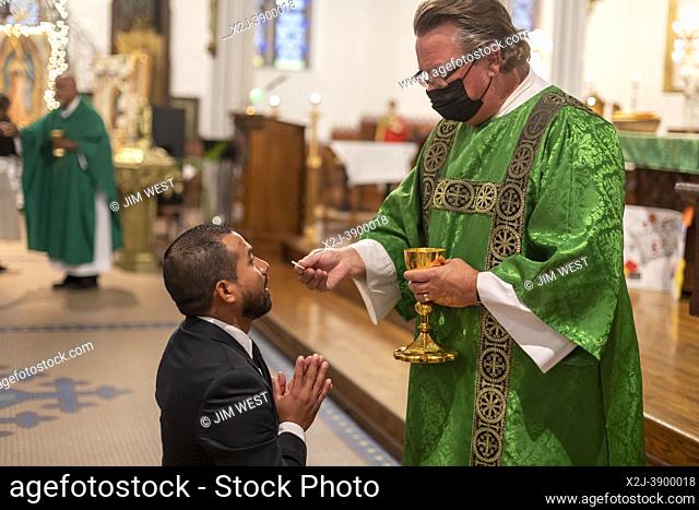 Detroit, Michigan - Msgr. Charles Kosanke gives communion at a mass at Holy Trinity Catholic Church in support of immigrants around the world