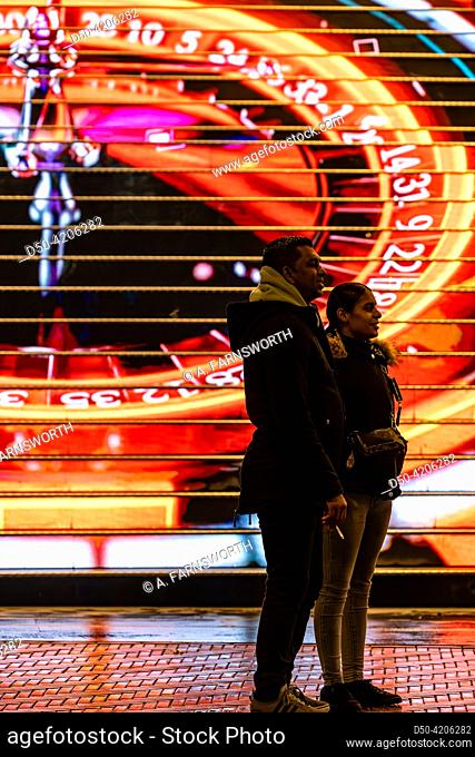 The Hague, Netherlands Pedestrians on the main shopping street Grote Marktstraat pass an illuminated staircase on a building with a projection of a roulette...
