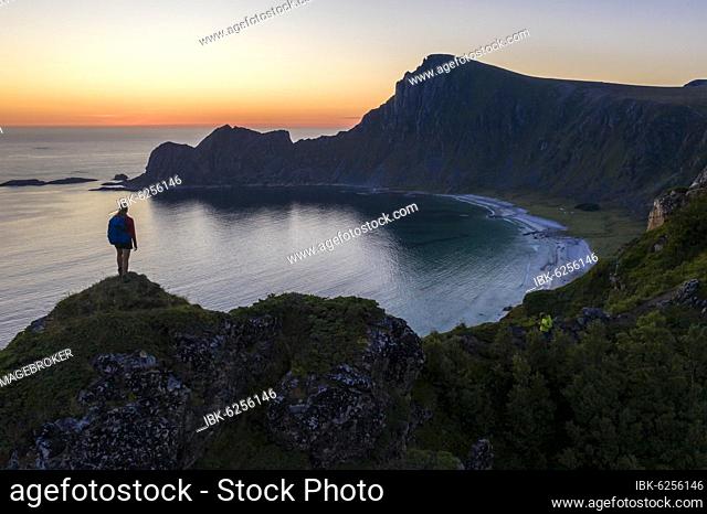 Evening mood, hiker on rocks, cliffs, beach and sea, in the back summit of the mountain Måtinden, near Stave, Nordland, Norway, Europe