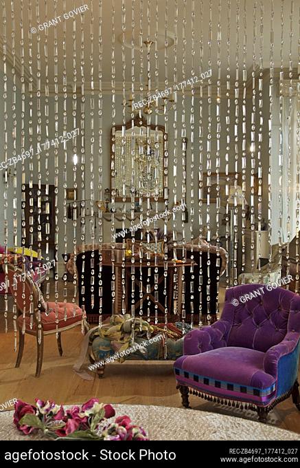 Beaded curtain with colourful upholstered armchairs