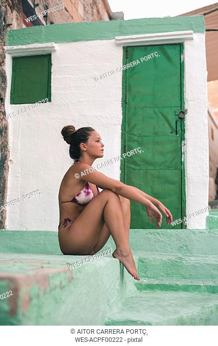 Teenage girl in sexy bikini, sitting on steps