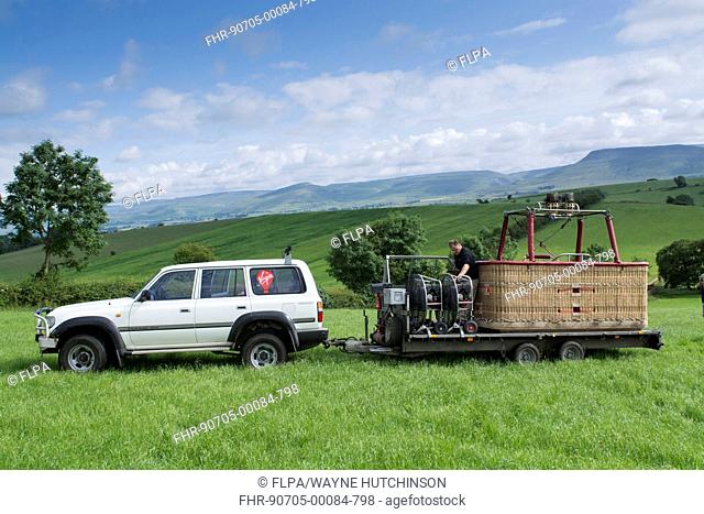 4x4 vehicle and trailer picking up hot-air balloon from field, Cumbria, England, July