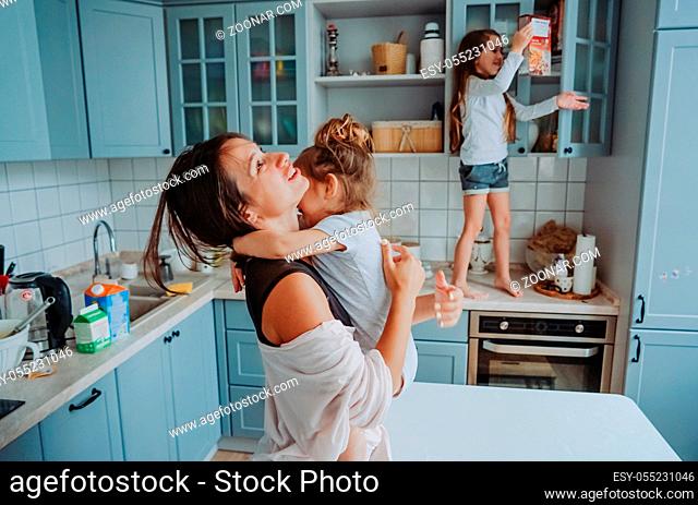 Attractive young woman and her two little cute daughters have fun in the kitchen