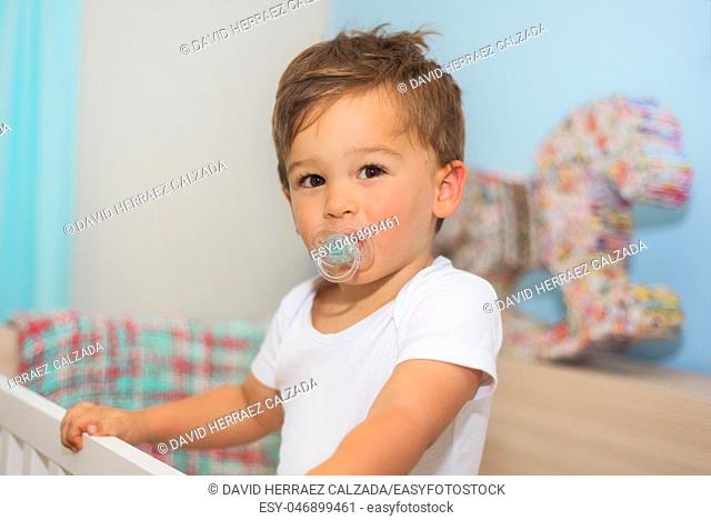 Adorable little boy in the crib with pacifier