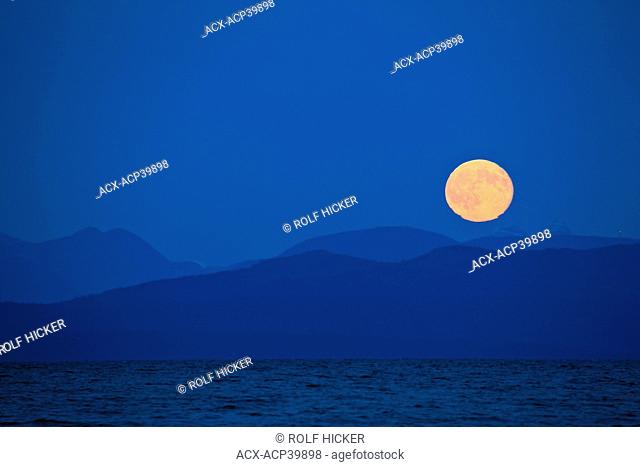 Full moon rising above the Coast Mountains of mainland British Columbia as viewed from Fillongley Provincial Park on the eastern shores of of Denman Island