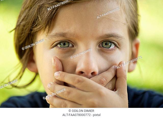 Boy covering mouth with hands