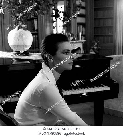 Giovanna Ralli sitting near a piano. Portrait of Italian actress Giovanna Ralli sitting at home near a piano. Rome, 1964