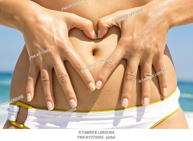 Woman making a heart shape with her finger on her stomach