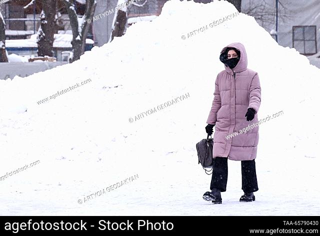RUSSIA, MOSCOW - DECEMBER 15, 2023: A woman walks past a snow pile at the VDNKh exhibition centre and park. Artyom Geodakyan/TASS