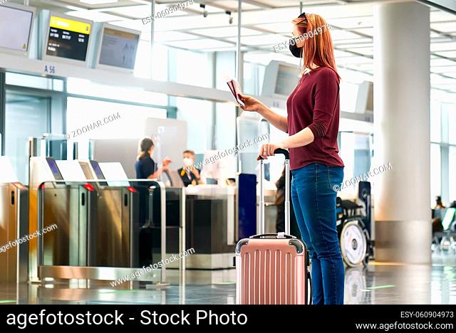 Young woman with protective face mask, passport and airline fly tickets at the international airport. Safe travel during the COVID 19 pandemic concept