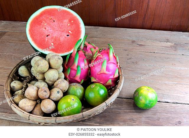 Asian fresh fruits. Langsat and watermelon and Orange and Dragon fruit in bamboo basket