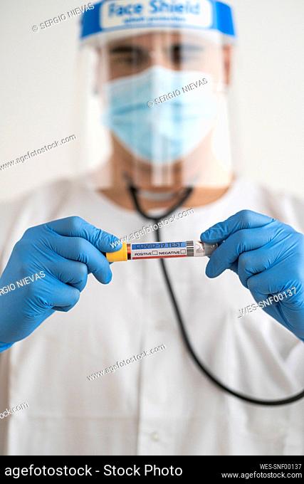 Man in protective wear holding covid-19 test