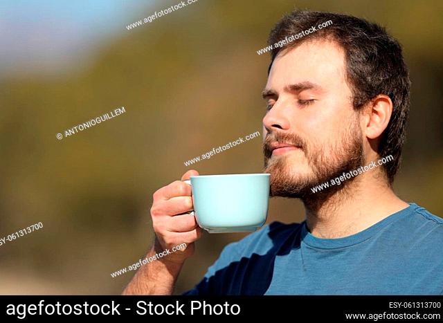 Relaxed man enjoying coffee cup standing in nature