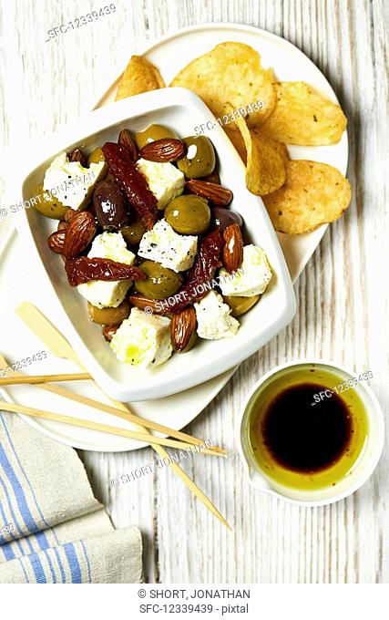 Feta with pickled olives, dried tomatoes, potato chips and olive oil