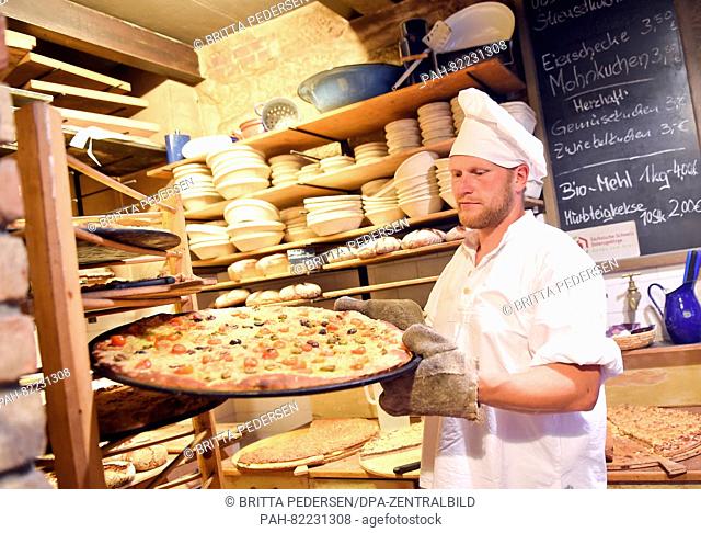 Master baker Alexander Mikat puts a pizza on a rack in the organic bakery of the Schmilka Mill in the Schmilka district of Bad Schandau, Germany, 19 July 2016