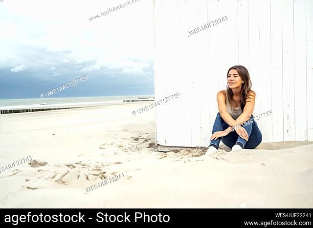 Smiling woman looking away while sitting at beach
