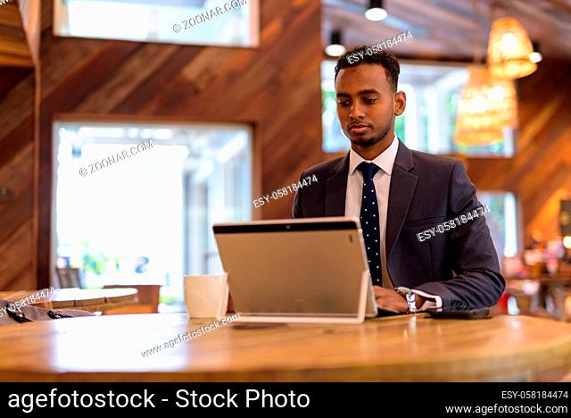 Portrait of young African businessman relaxing inside coffee shop