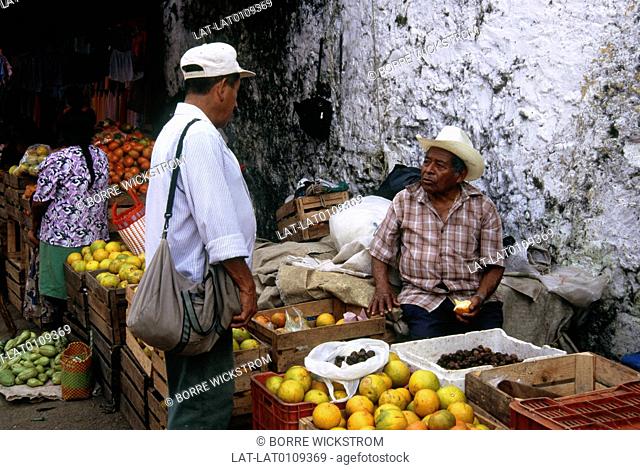 Market stall in street. Fruit on display. Oranges, citrus. Two men talking