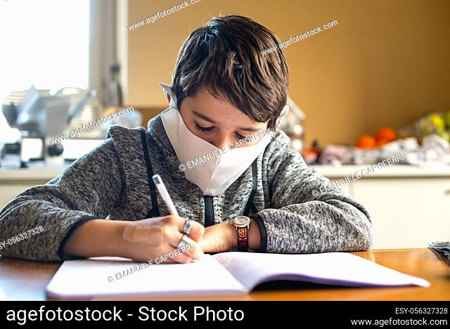 child performs homework at home with hygiene mask and covid