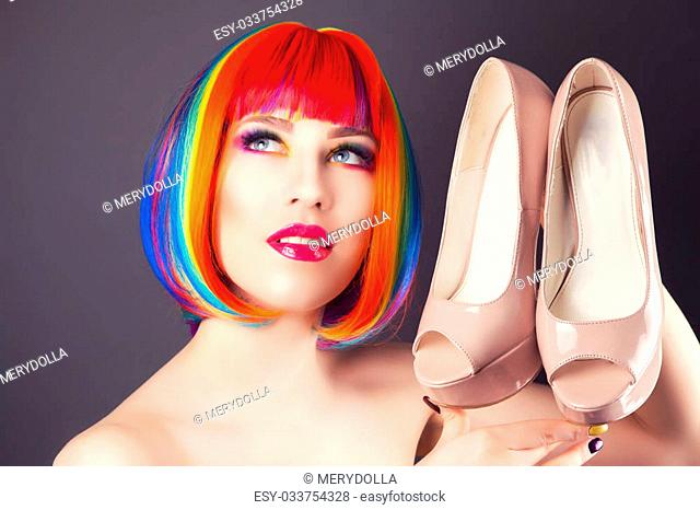 beautiful woman wearing colorful wig with heels in hands