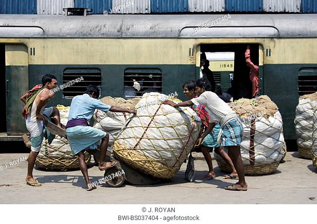 pushing cotton bales in a railway station, India, Kolkata