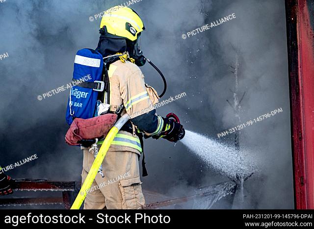 01 December 2023, Berlin: Firefighters extinguish a simulated room fire during a demonstration of a fire during the Christmas season on the grounds of the...