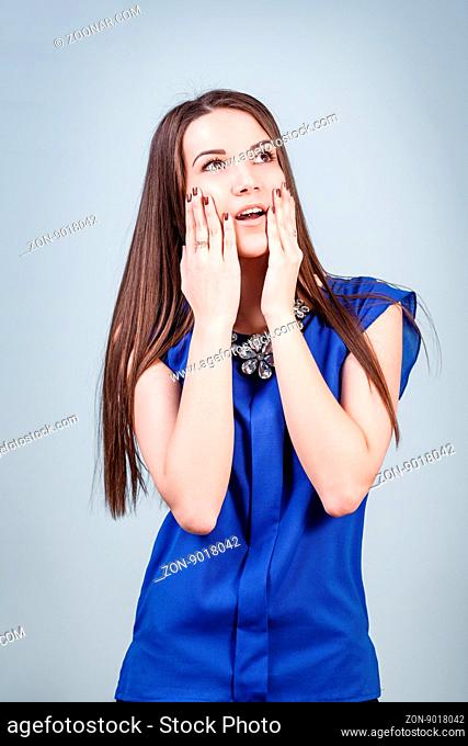 Young surprised woman on the gray background