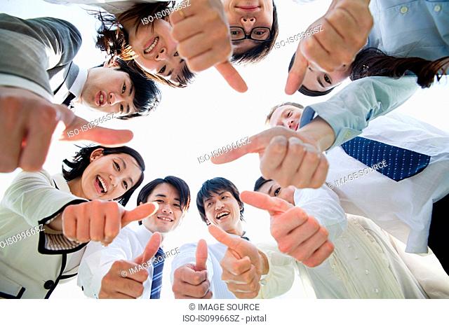 Businesspeople in a circle with thumbs up
