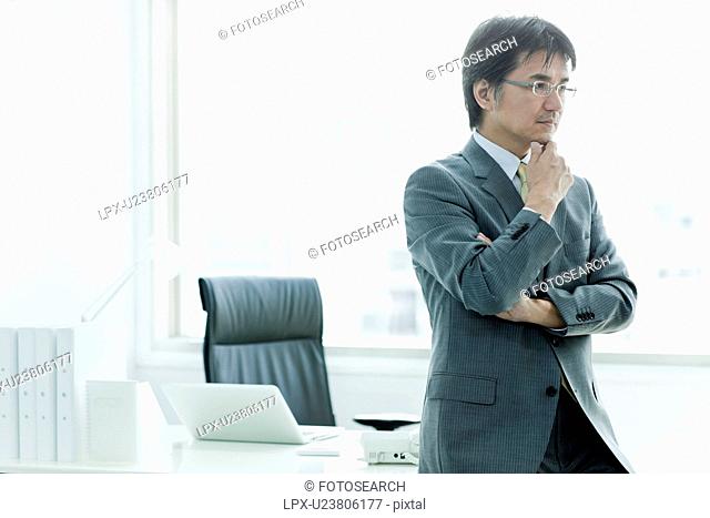 Businessman Sat On Desk, Thinking