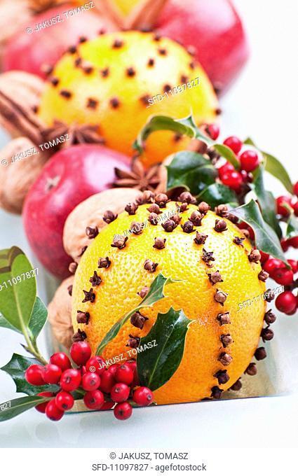 Oranges pierced with cloves, holly berries, apples, walnuts, star anies and cinnamon sticks