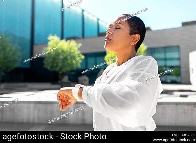 young woman with smart watch breathing outdoors