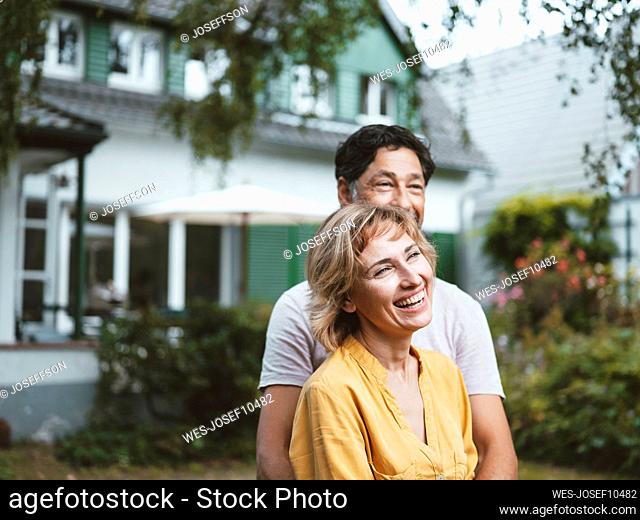 Cheerful mature woman with man standing in front of house