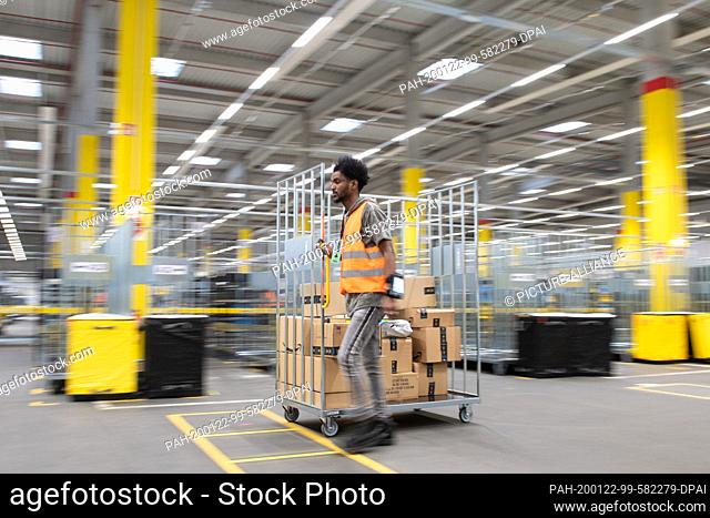 22 January 2020, Saxony, Lampertswalde: An Amazon sorting employee pulls a cart with parcels in a distribution centre. In the hall