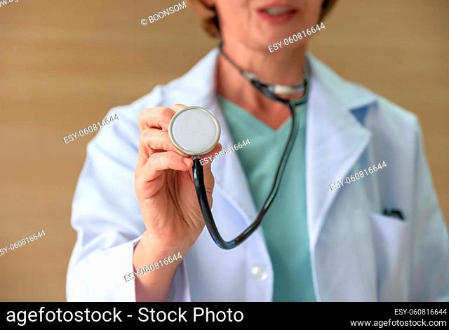 Cropped of female doctor in white coat uniform using medical stethoscope . Healthcare and insurance concept