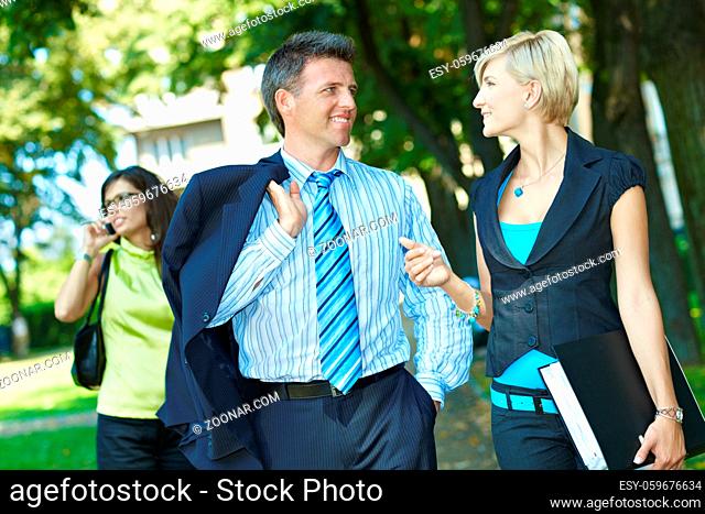 Businessman and businesswoman walking and talking in downtown park
