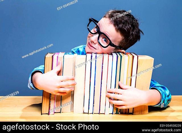 Little pupil in glasses hugs books. Education concept. Getting elementary knowledges in school
