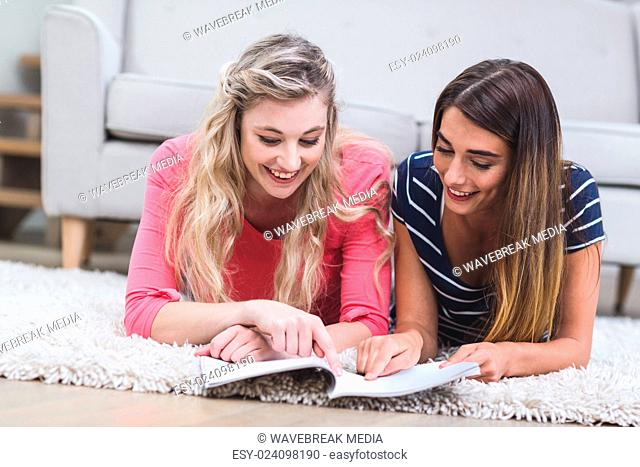 Two beautiful women reading a magazine in living room