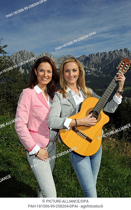 06 October 2018, Austria, Ellmau: Sisters Sigrid (L) and Marina Hutterer from the Austrian Schlager vocal duo standing with a guitar on the Ruebezahlalm near...