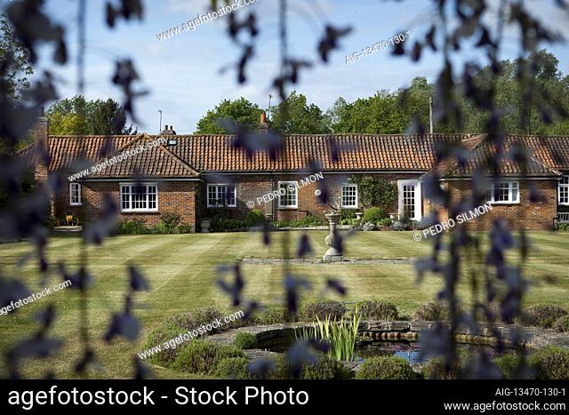 A curtain of, Wisteria floribunda 'Macrobotrys', obscures the house, once a couple of tiny, two-room cottages that have been merged and extended throughout the...