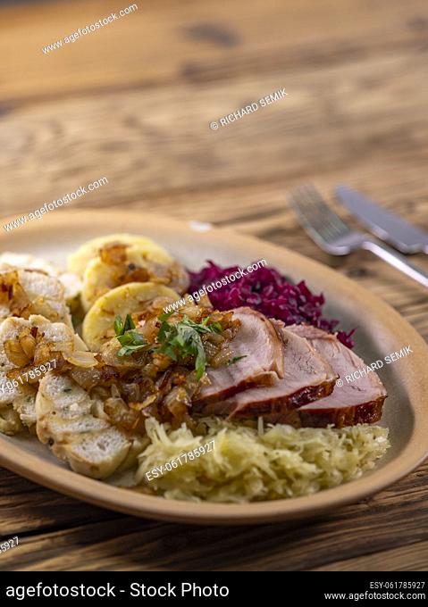 smoked meat served with red and white cabbage and two kinds of dumplings