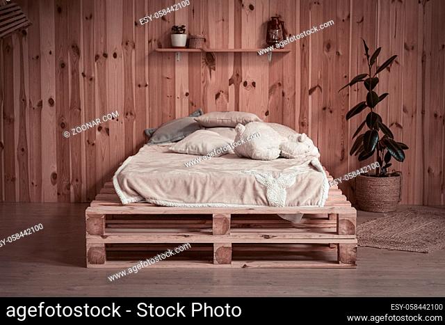 Simple cozy bed in wooden apartment. Front view. Comfortable place or space for rest