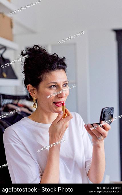 Smiling woman applying lipstick