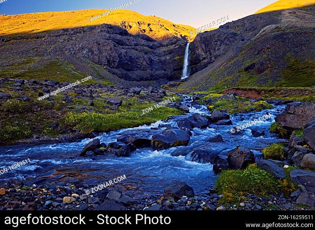 Fluss Gilsá mit Wasserfall im Tal des Berges Hoettur und Sandfell am Abend, Ostisland, Island, Europa