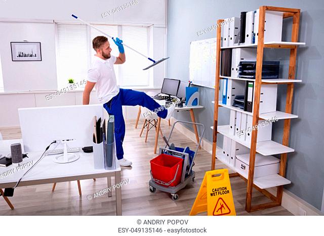 Man Janitor Slipping While Mopping Floor In Modern Office