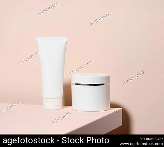 empty white plastic tube andjar for cosmetics stands on a beige background. Containers for cream, shampoos, liquid substances. Branding, template
